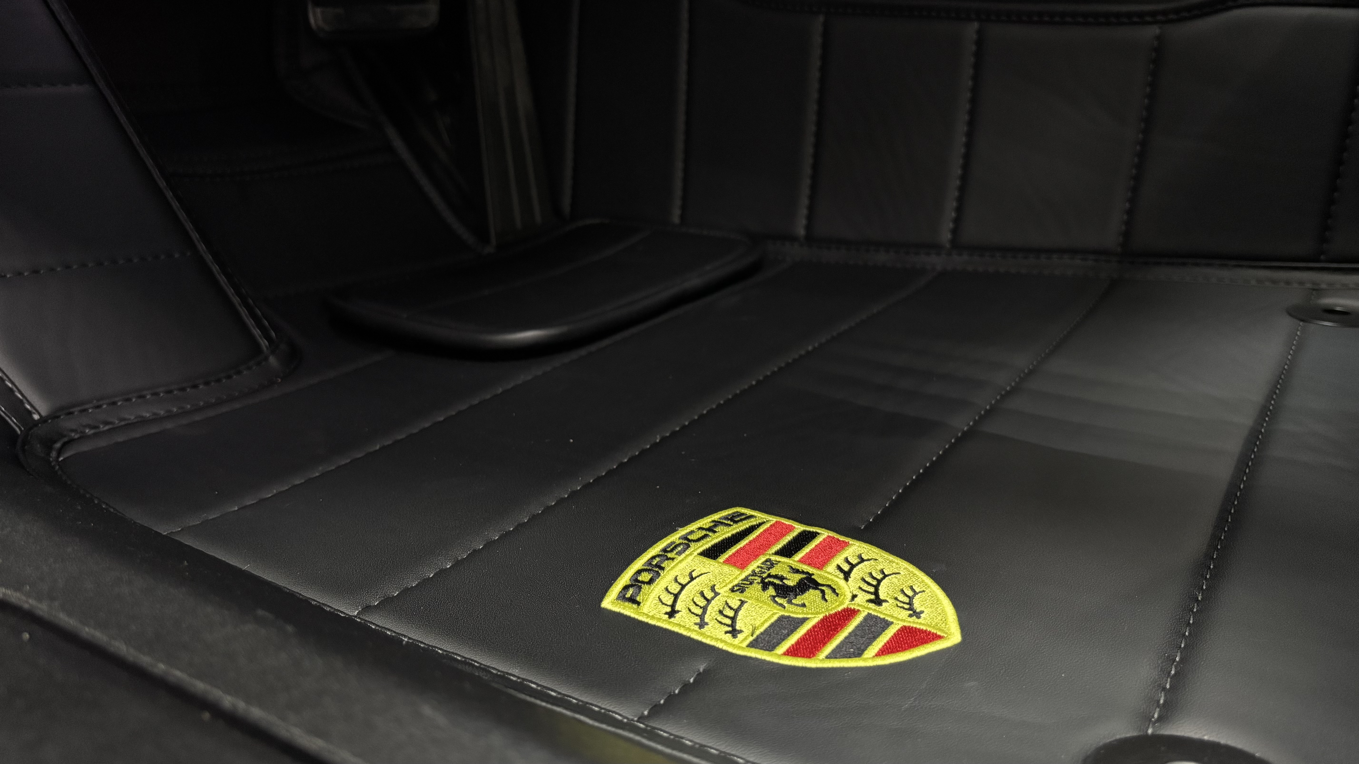 Ровная строчка и вышивка Porsche на коврике крупным планом