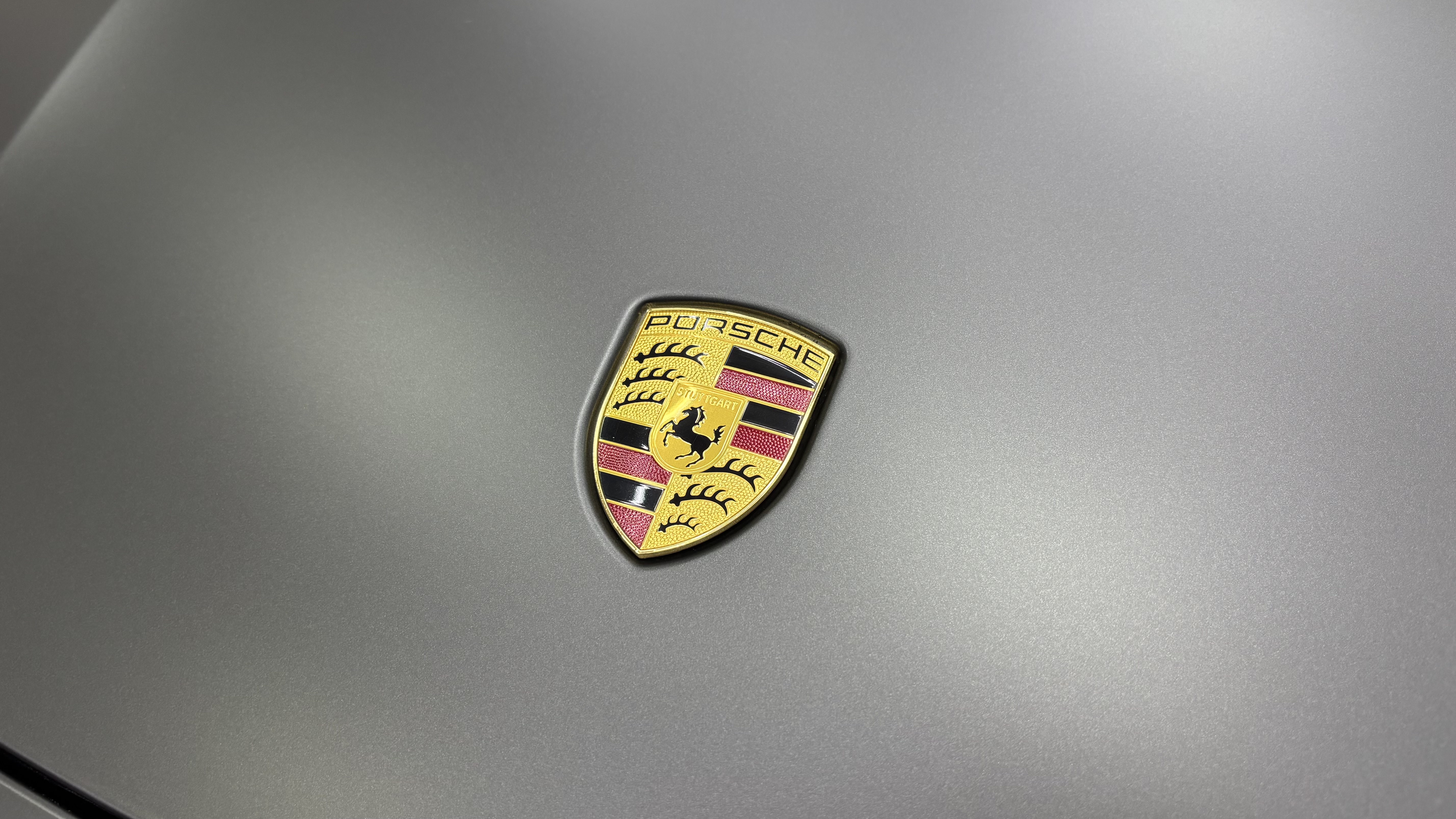 Эмблема Porsche на матовом капоте