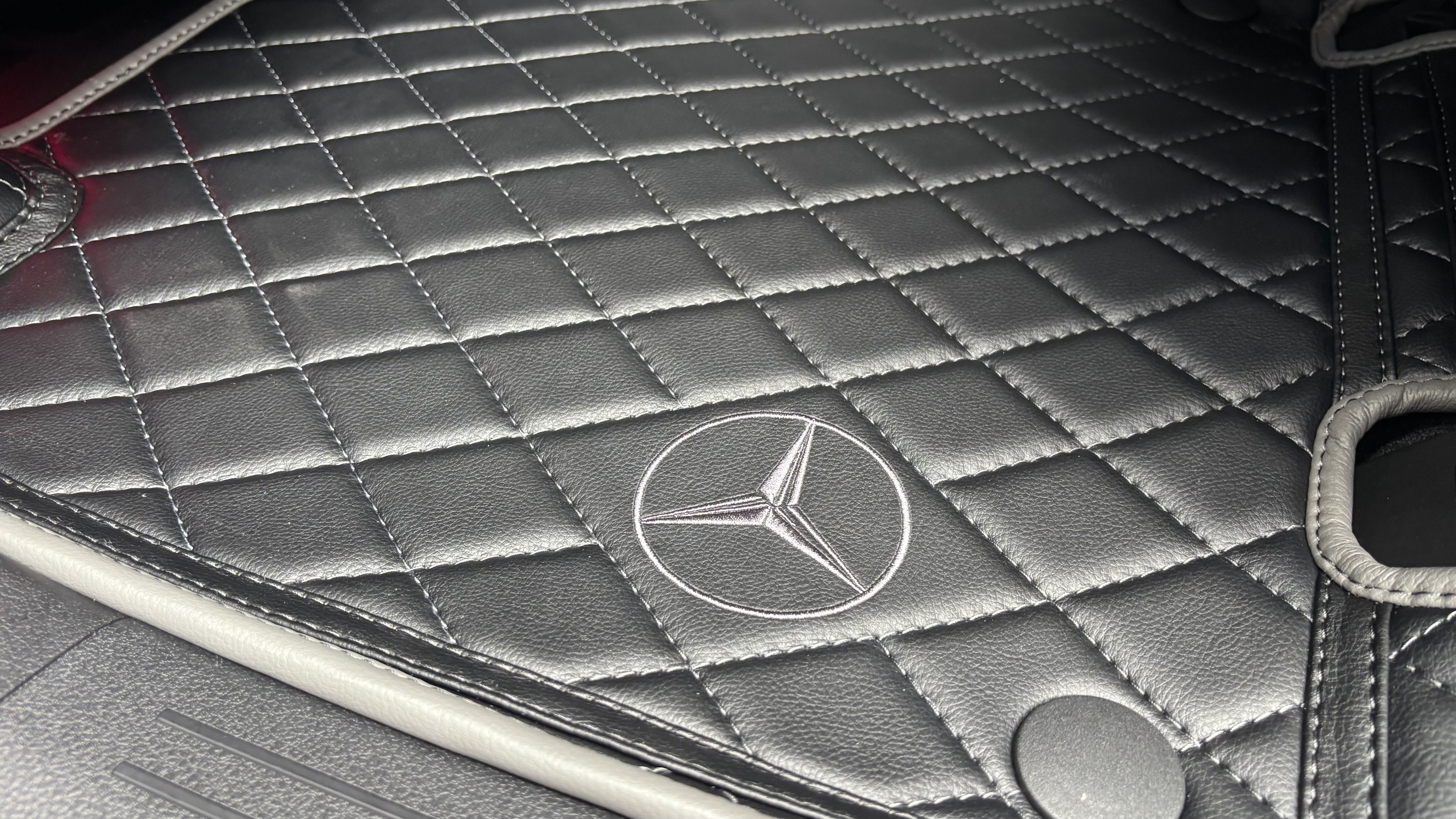 Строчка и фирменная вышивка на 3D-коврике Mercedes крупным планом